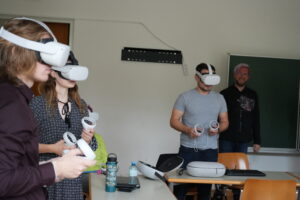 Studierende beim Ausprobieren der VR-Brillen unter den Augen von Peter Färberböck